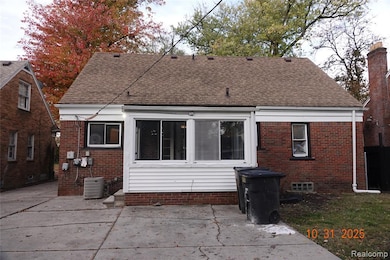 Rear view of property with roof with shingles, brick siding, and a patio