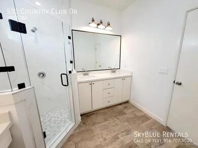 Bathroom with tile flooring, dual bowl vanity, and an enclosed shower