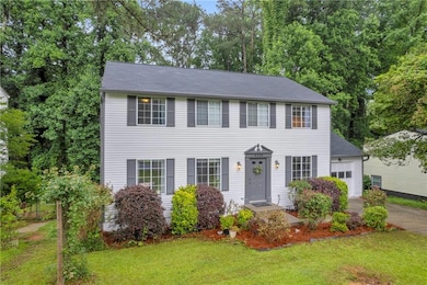 Colonial house featuring an attached garage, a front lawn, and driveway