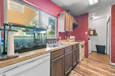 Kitchen with a textured ceiling, white appliances,
