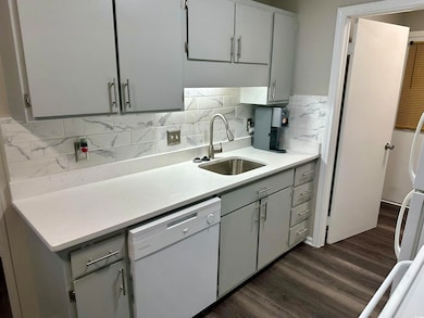 Kitchen with white dishwasher, dark wood-style flo
