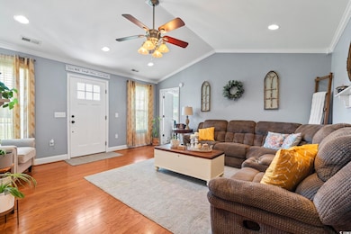 Living area featuring wood finished floors, a ceiling fan, ornamental molding, recessed lighting, and baseboards