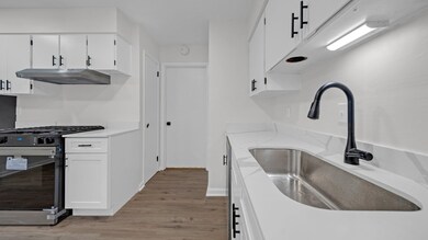 Kitchen with white cabinets, sink, light hardwood 