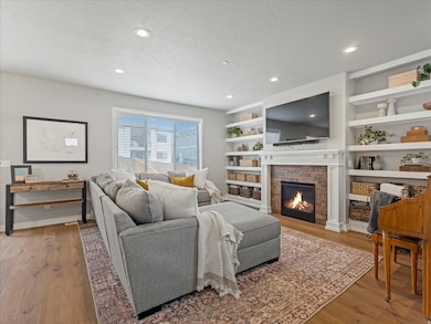 Living area featuring a textured ceiling, a brick fireplace, recessed lighting, light wood finished floors, and built in features