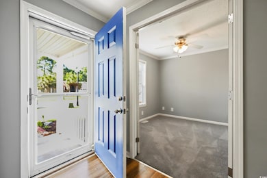 Foyer entrance with ornamental molding, baseboards, ceiling fan, and carpet floors