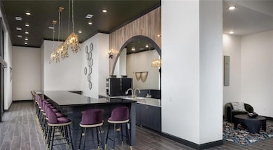 Bar with wood tiled floors, arched walkways, and hanging light fixtures