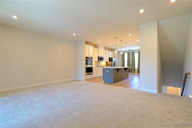 Kitchen with light colored carpet, an island with sink, appliances with stainless steel finishes, open floor plan, and recessed lighting