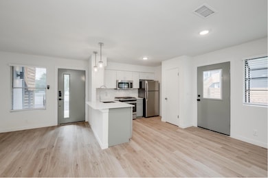Kitchen featuring stainless steel appliances, a peninsula, recessed lighting, light wood-style flooring, and pendant lighting