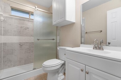 Bathroom with tile patterned floors, toilet, vanity, and an enclosed shower