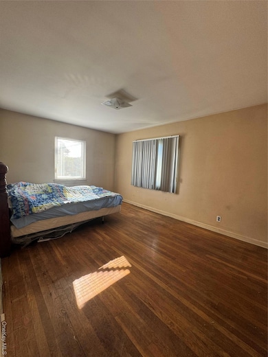 Bedroom with dark wood-style flooring and baseboards