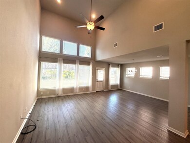 Unfurnished living room featuring dark wood-style flooring, a high ceiling, and ceiling fan