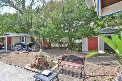 View of rear garden with 2 storage sheds and a crushed shell drive from the alley