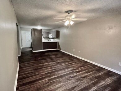 Unfurnished living room featuring a textured ceiling, a ceiling fan, and dark wood finished floors