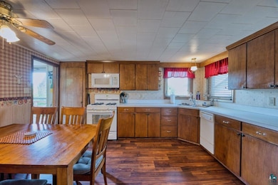 Kitchen featuring white appliances, light countertops, dark wood finished floors, ceiling fan, and wallpapered walls