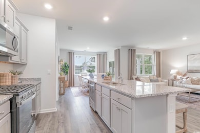 Kitchen featuring sink, a breakfast bar, appliances with stainless steel finishes, a center island with sink, and light wood-type flooring