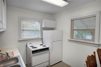 Kitchen featuring baseboards, white appliances, a