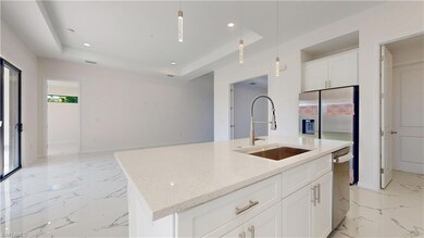 Kitchen with a sink, light marble finish flooring, recessed lighting, a raised ceiling, and a kitchen island with sink
