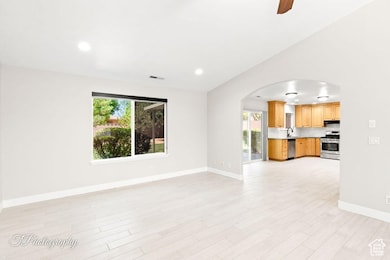 Unfurnished living room featuring arched walkways, recessed lighting, ceiling fan, and light wood-style floors