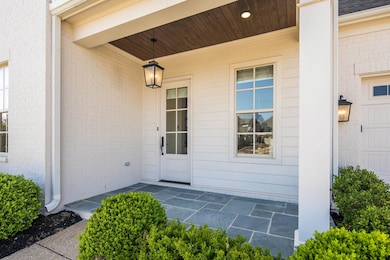 Property entrance with covered porch and brick sid