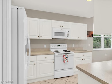 Kitchen with white appliances, light tile patterne
