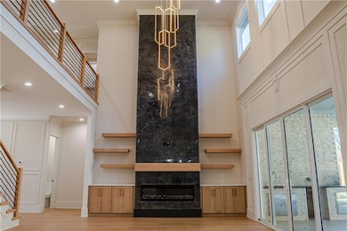 Unfurnished living room featuring stairs, recessed lighting, light wood-style flooring, a large fireplace, and a high ceiling