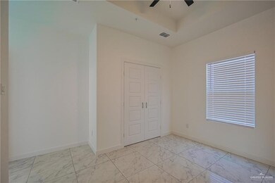 Unfurnished bedroom featuring light marble finish flooring, a closet, a tray ceiling, and ceiling fan