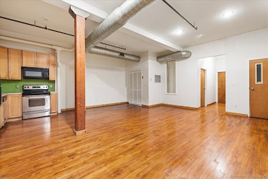 Open floor plan living room, dining room and kitchen with 10+ foot ceilings, exposed wood beams and ductwork