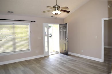 Entrance foyer with light wood-style floors, visible vents, vaulted ceiling, and a ceiling fan