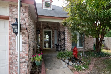 Covered entry flanked by flower beds with flagpole