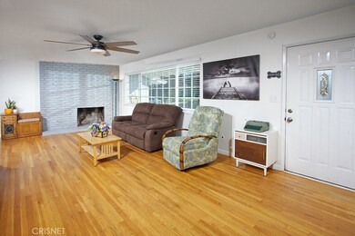 The living room is bathed in natural light from sparkling picture windows and is further enhanced by a raised-hearth brick fireplace and original Oak hardwood floors.