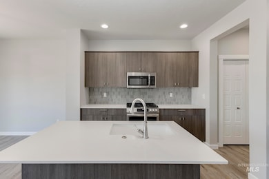 Kitchen with appliances with stainless steel finishes, modern cabinets, light wood finished floors, a kitchen island with sink, and recessed lighting