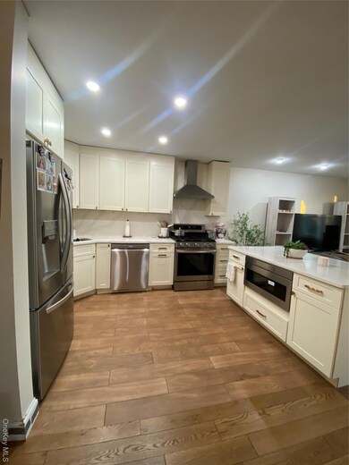 Kitchen with white cabinetry, appliances with stainless steel finishes, dark wood-type flooring, ventilation hood, and recessed lighting