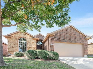 View of front of property featuring driveway, an attached garage, brick siding, and stone siding