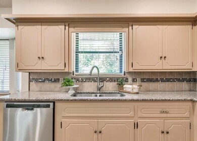 Kitchen featuring sink, tasteful backsplash, white cabinetry, and stainless steel dishwasher