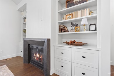 Detailed view of wood finished floors, built in shelves, and a glass covered fireplace