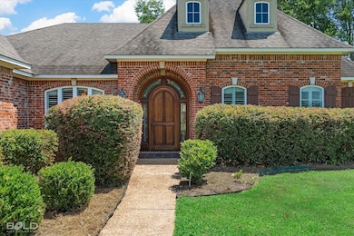 Entrance to property featuring brick siding, a shingled roof, and a yard