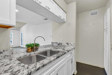 Kitchen featuring white cabinetry, a sink, light s