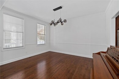 Unfurnished dining area featuring ornamental molding, dark wood-style floors, and a chandelier