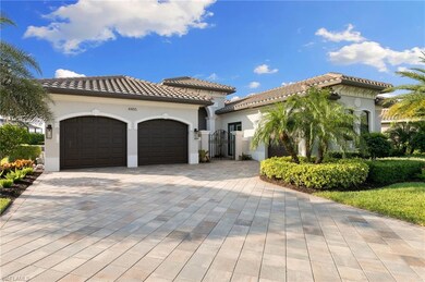 Mediterranean / spanish house featuring decorative driveway, an attached garage, stucco siding, a tile roof, and a gate