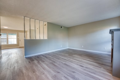 Unfurnished room with a textured ceiling, baseboards, and wood finished floors