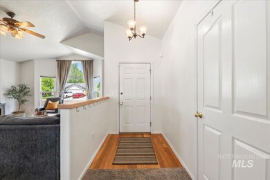 Foyer entrance with vaulted ceiling, wood finished floors, a chandelier, ceiling fan, and a textured ceiling