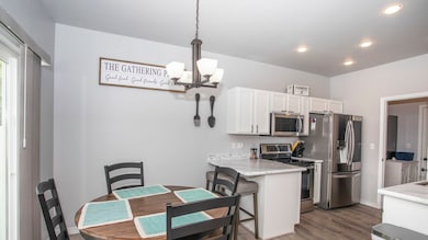Kitchen with stainless steel appliances, decorative light fixtures, white cabinets, a chandelier, and a peninsula