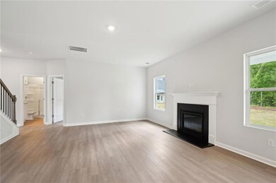 Unfurnished living room featuring wood finished floors, stairs, a glass covered fireplace, and recessed lighting