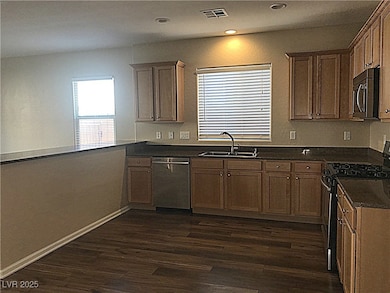 Kitchen featuring stainless steel appliances, dark wood finished floors, brown cabinetry, and recessed lighting