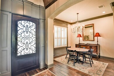 Foyer featuring ornamental molding, dark wood-type flooring, and an inviting chandelier