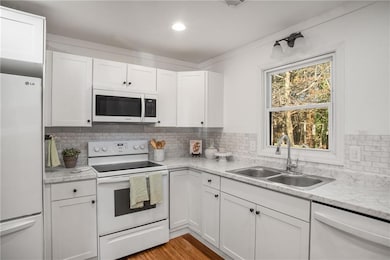 Kitchen with backsplash, white cabinetry, sink, an
