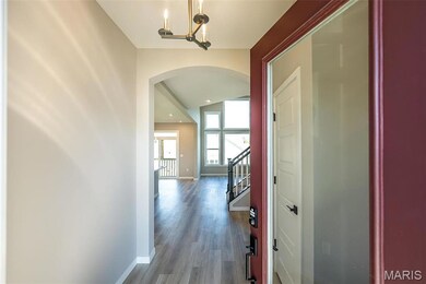 Hall with wood-type flooring and a chandelier