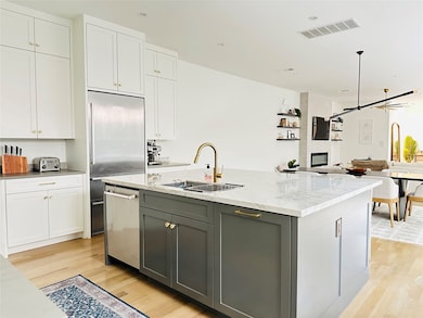 Kitchen featuring gray cabinets, white cabinetry, a center island with sink, and open floor plan
