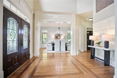 Foyer featuring a high ceiling, french doors, a chandelier, decorative columns, and crown molding