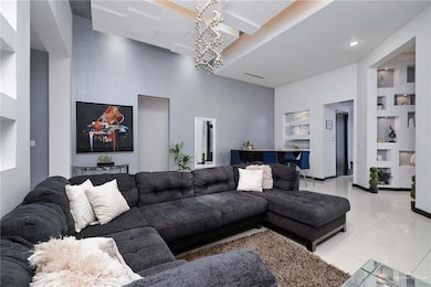 Living area with built in shelves, light tile patterned flooring, a chandelier, a towering ceiling, and recessed lighting